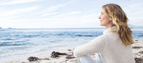 Frau sitzt am Meer